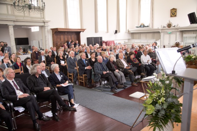 De zaal in de kerk gevuld met publiek