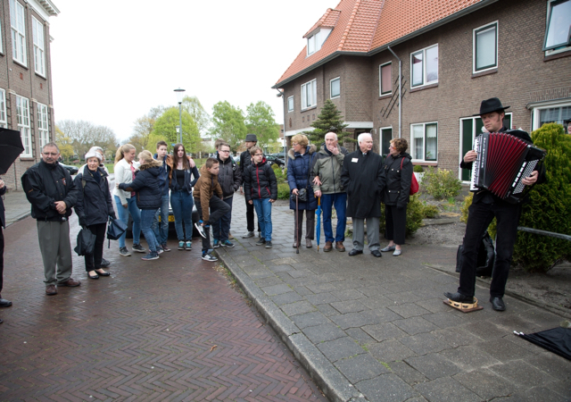 Publiek bij de onthulling van herdenkingsstenen luisterend naar live muziek